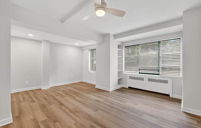 A room with a ceiling fan and a window with blinds.