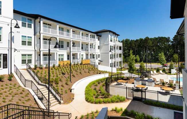 a view of the exterior of an apartment building with a courtyard and benches at The Quincy Apartments, Acworth, GA