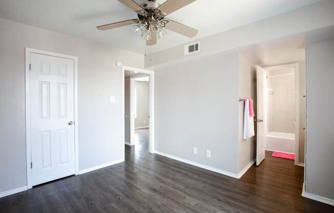 A room with a ceiling fan and wooden floors.