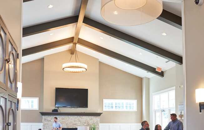 a large lobby with people sitting at tables and chairs at The Winhall of Williams Pointe Apartments, Waukee, IOWA