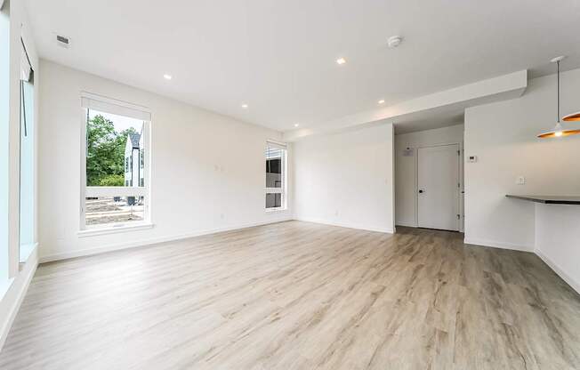 A spacious room with wooden flooring and white walls.