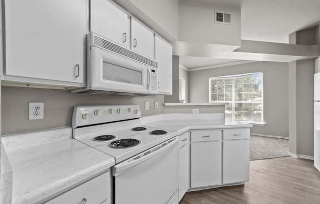 A white kitchen with a stove, oven, microwave, and refrigerator.