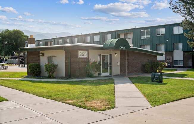 an apartment building with a green roof and a sidewalk