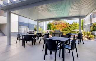 a patio with tables and chairs and a grill