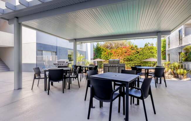 a patio with tables and chairs and a grill