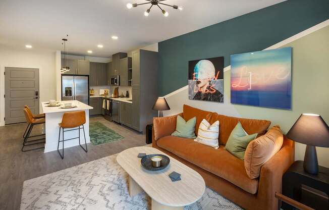 a living room with an orange couch and a kitchen with a table and chairs