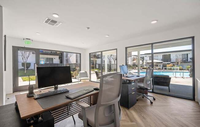 A modern office with a view of a pool and trees outside the windows.