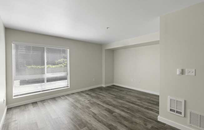 a bedroom with a large window and hardwood floors at Excalibur Apartment Homes, Bellevue, WA