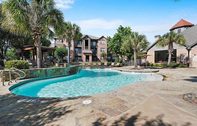 A swimming pool surrounded by palm trees and a building in the background.