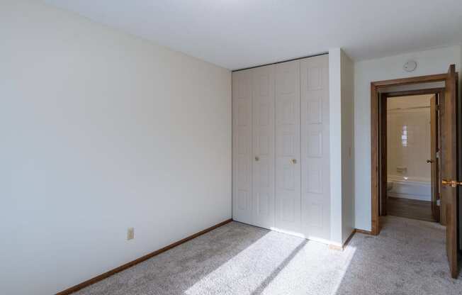 a bedroom with a closet and a door to a bathroom. Fargo, ND Windsor Apartments