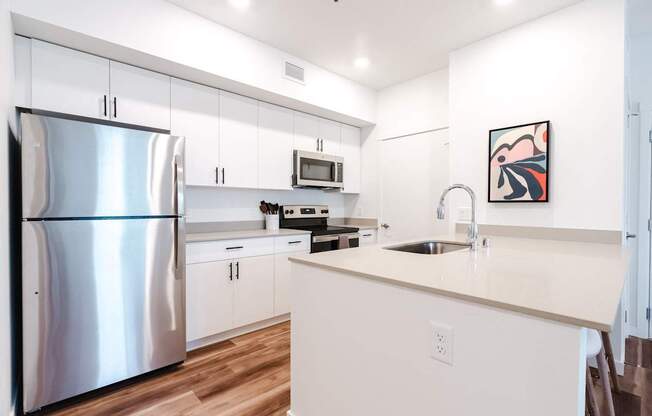 A modern kitchen with a stainless steel refrigerator and white cabinets.