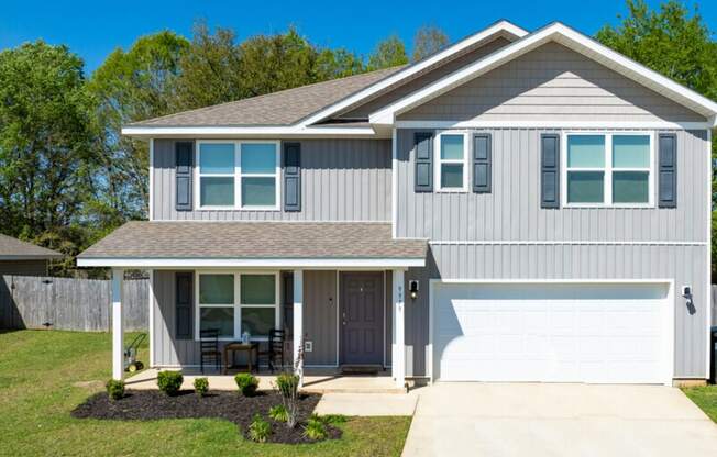 a gray house with a white garage door and a lawn