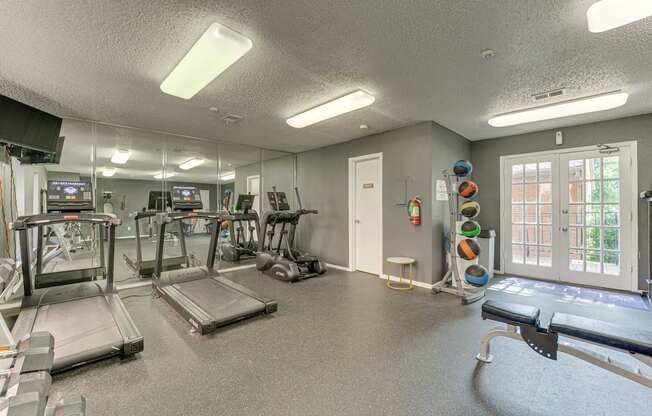 A gym with treadmills, exercise equipment, and a mirrored wall at Copper Hill Apartments, Texas, 76021