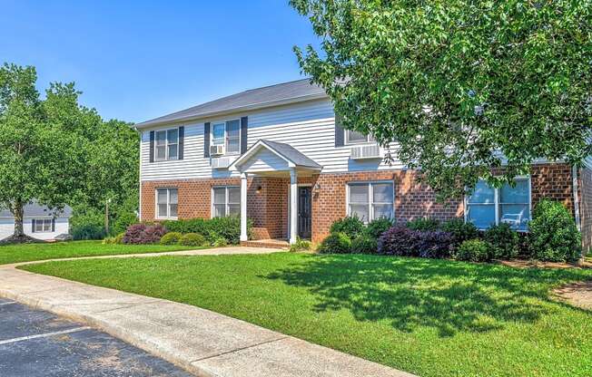 the front of a house with a lawn and trees