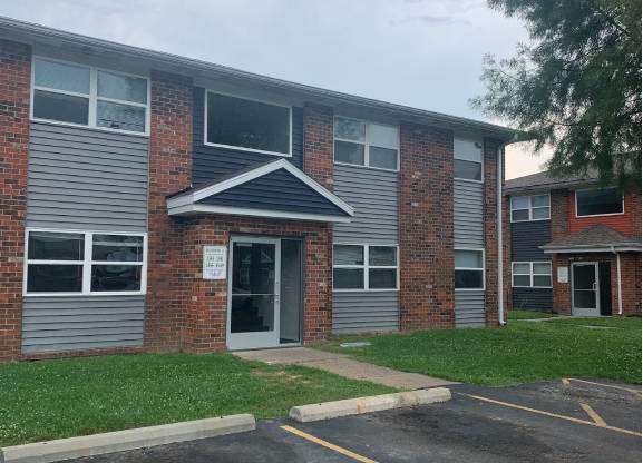 the front of a building with a parking lot and grass