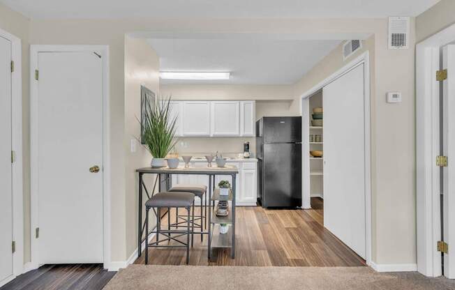 A kitchen with white cabinets and a black fridge.