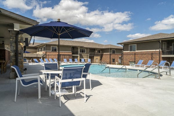 Resort-style pool with chairs and umbrellas at The Villas at Falling Waters in west Omaha