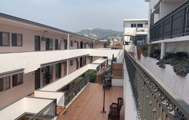 A balcony with a chair and a table is overlooking a street.