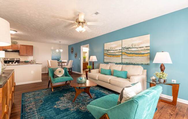A living room with a blue rug and a painting on the wall.
