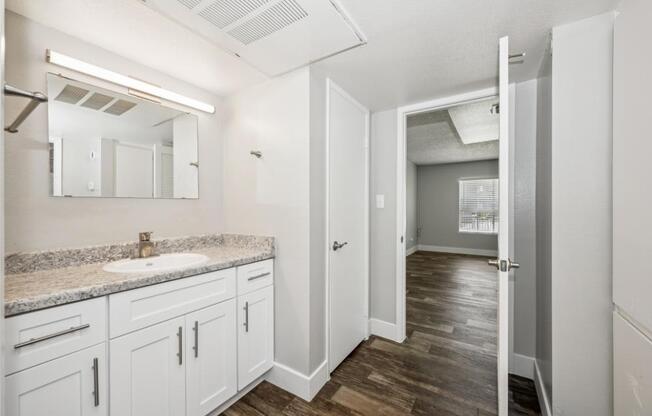 Model bathroom with a sink, mirror, and cabinets.