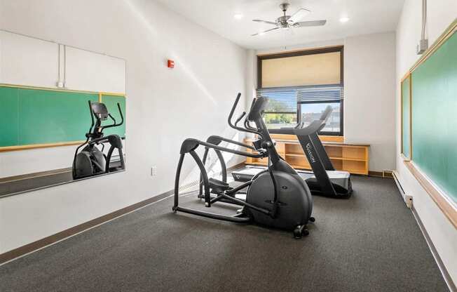 Muskego School's fitness center with cardio equipment, wall chalkboards, mirrors, and a ceiling fan