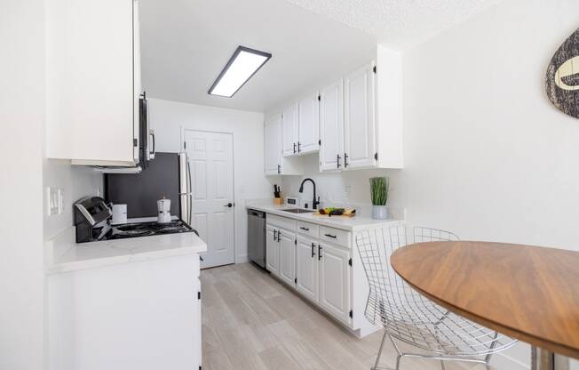 a white kitchen with white cabinets and a wooden table and counter top at Campbell West Apartments, Campbell, CA