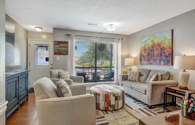 a living room with a couch and chairs and a window