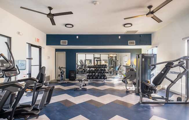a gym with weights and cardio machines and ceiling fans
