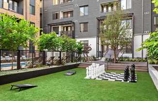 A chess set sits on a green lawn in front of a building.