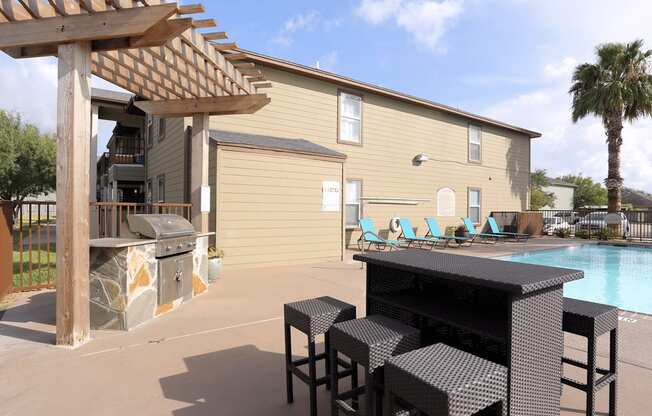 A patio with a table and chairs and a pool.