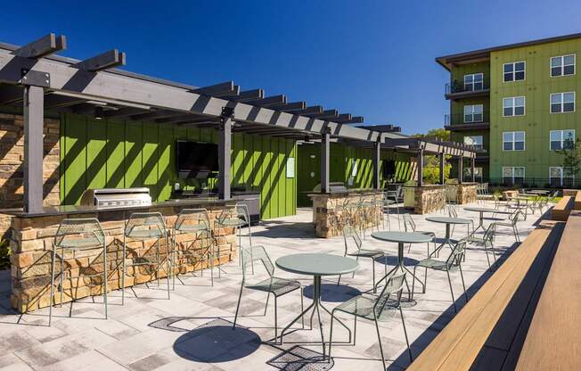 A patio with tables and chairs is covered by a roof.