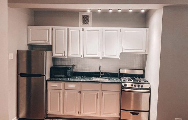 a kitchen with white cabinets and a stainless steel refrigerator