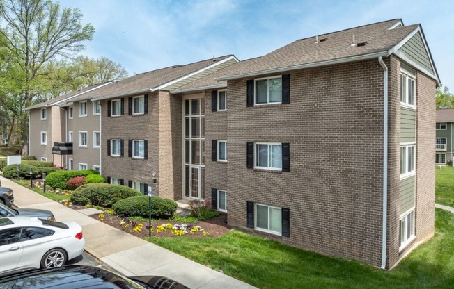A brick apartment building with a car parked in front.