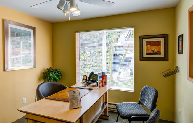 an office with a desk and chairs and a large window