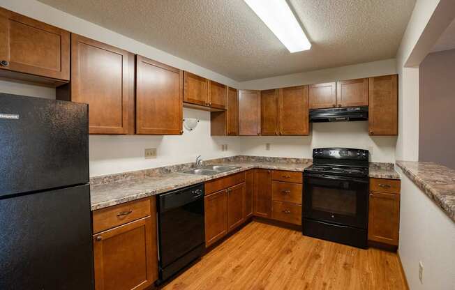 A kitchen with wooden cabinets and black appliances. Fargo, ND Park Place Apartments