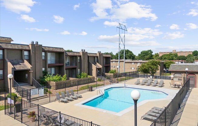 A pool surrounded by a black fence and chairs.