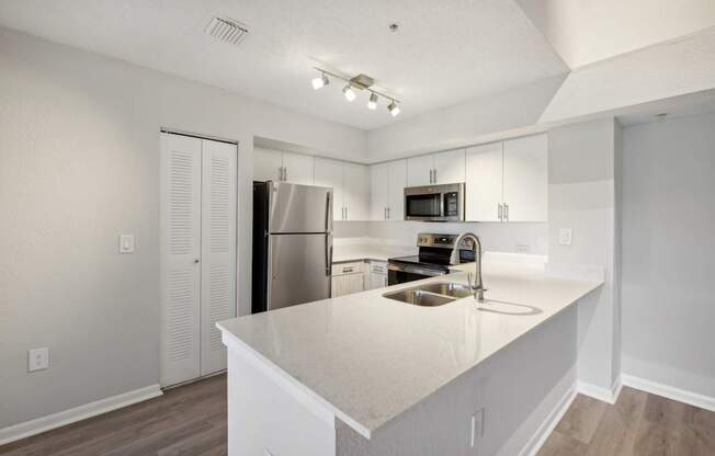 A kitchen with white cabinets and a stainless steel refrigerator.
