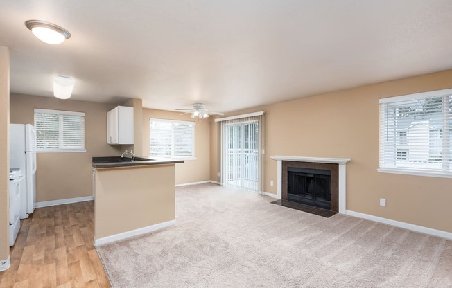 an empty living room with a fireplace and a kitchen