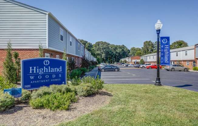 a sign for highland woods apartments in front of a parking lot