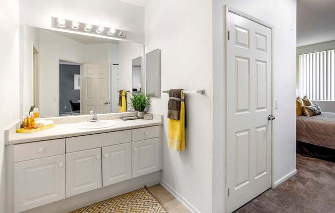 A bathroom with a white door and a mirror above the sink.