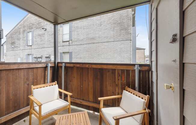 two chairs and a table on a balcony with a sliding glass door