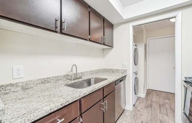 A kitchen with brown cabinets and a granite countertop.