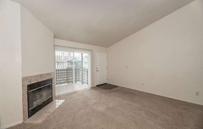 A large, empty room with a fireplace and a sliding glass door at Pepperwood Apartments, California, 95661