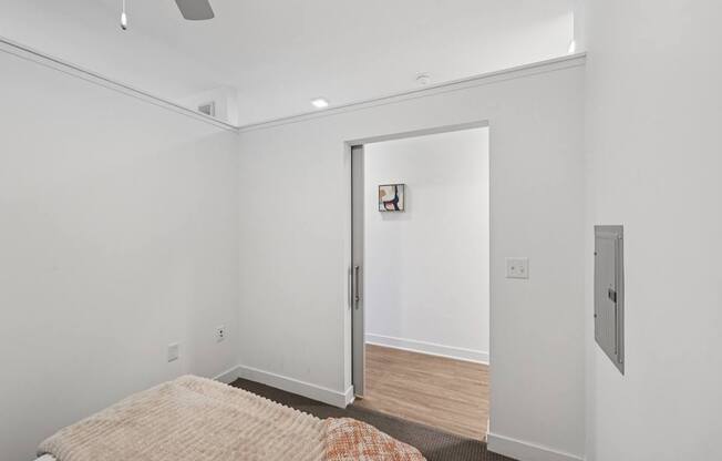 A bedroom with a bed and a door leading to another room.