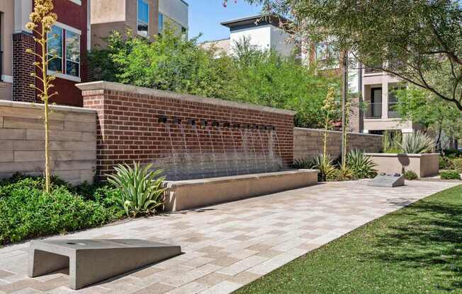 A modern garden with a brick wall and a concrete bench.