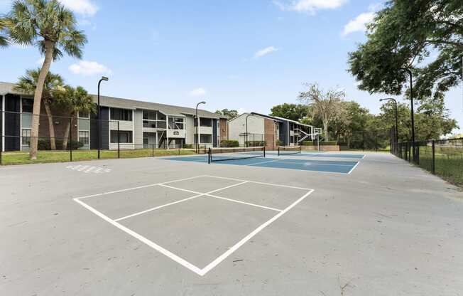 an empty basketball court with apartments in the background