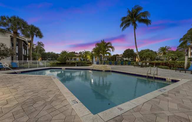 a swimming pool with palm trees and a building in the background