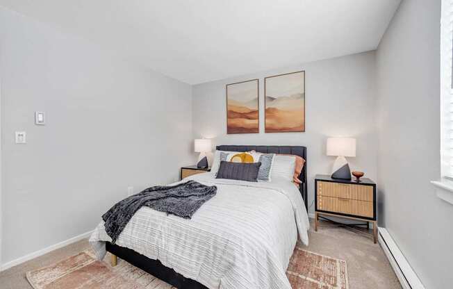 A bedroom with a bed, nightstands, and pictures on the wall.