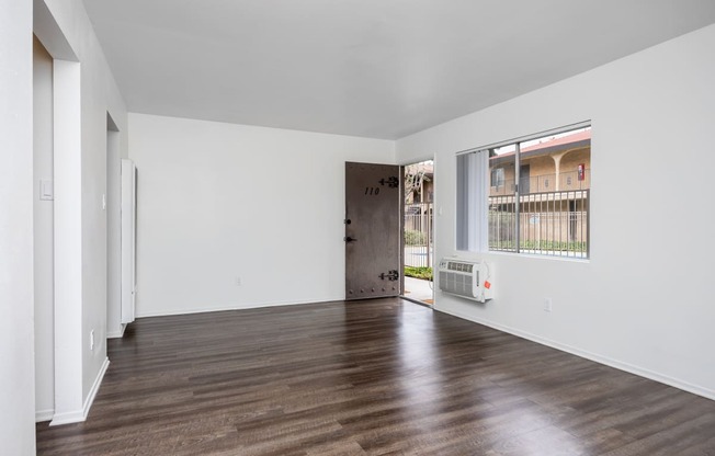 a living room with white walls and a large window and wooden floors