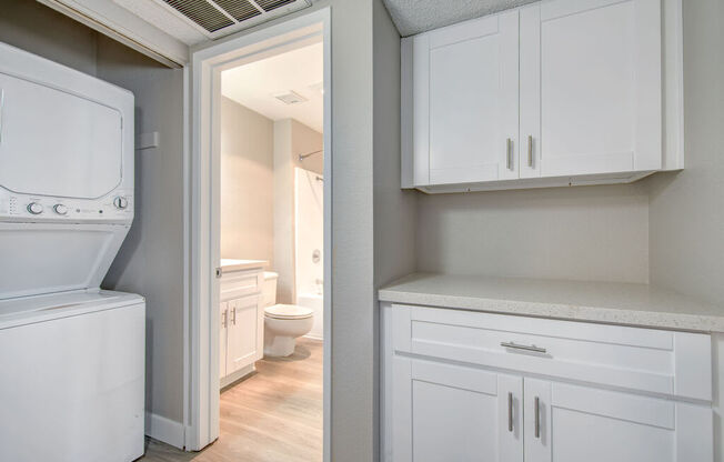 a laundry room with white cabinets and a white washer and dryer at La Jolla Blue, San Diego California